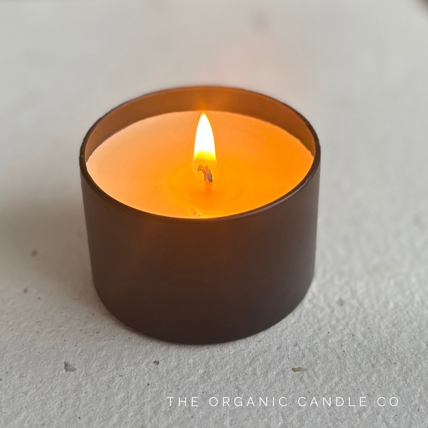 Black candle with a lit flame on a neutral background