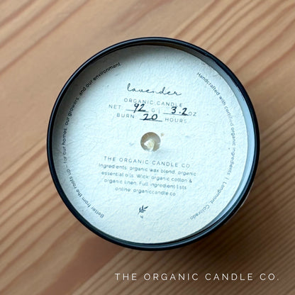 Candle jar with label on a wooden surface, featuring 'The Organic Candle Co.'