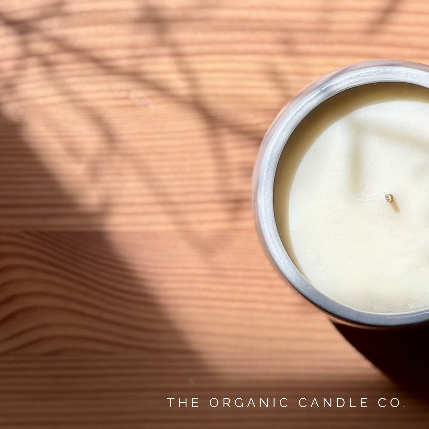 Candle on a wooden surface with 'The Organic Candle Co.' branding.