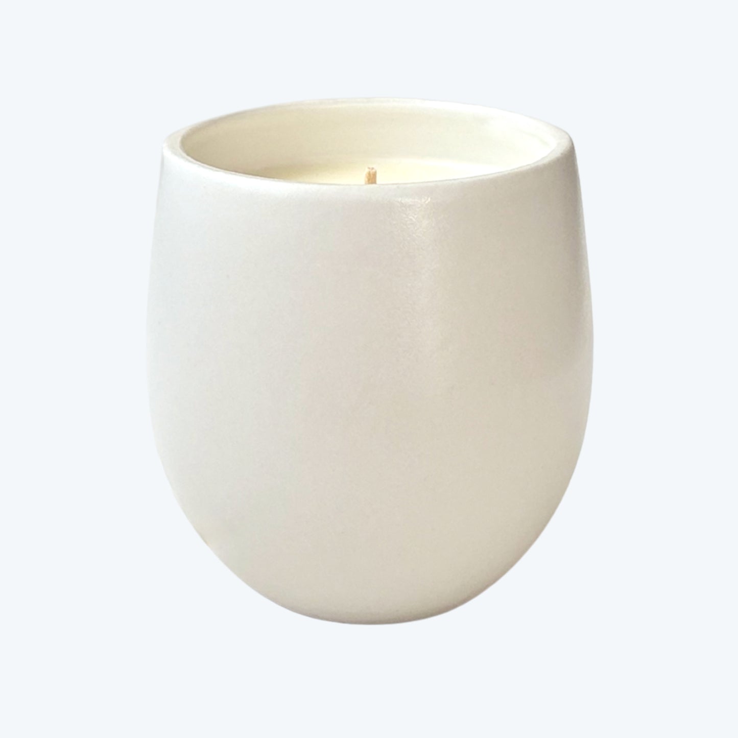 White organic candle in ceramic container on a neutral background