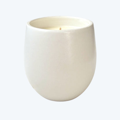 White organic candle in ceramic container on a neutral background