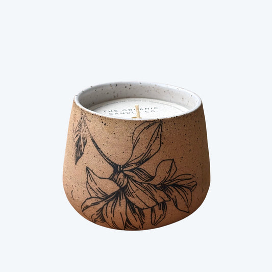 Organic candle in ceramic vessel with botanical design on a neutral background
