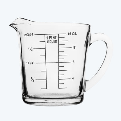 Clear glass measuring cup with measurement markings on a neutral background