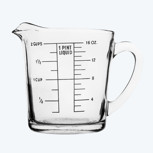 Clear glass measuring cup with measurement markings on a neutral background