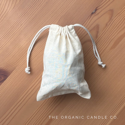 Small drawstring bag on a wooden surface with 'The Organic Candle Co.' branding.