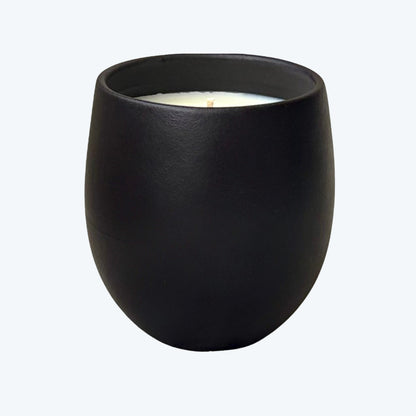 Organic candle in black ceramic vessel on a neutral background
