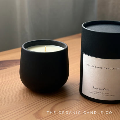 Organic candle in black ceramic vessel and packaging of The Organic Candle Co on a wooden surface