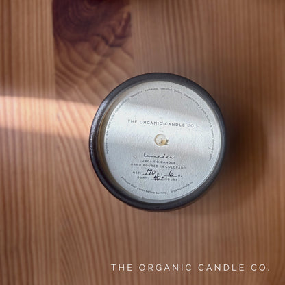 Organic candle in black ceramic vessel with label on a wooden surface, featuring 'The Organic Candle Co.'