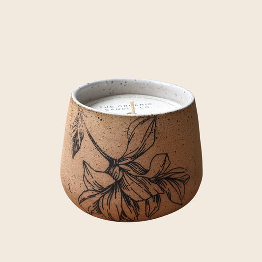 Organic candle in ceramic vessel with botanical design on a neutral background