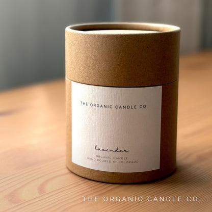 Cylindrical brown candle container with 'The Organic Candle Co' label on a wooden surface.